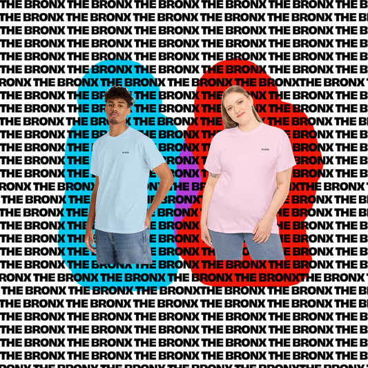 A man and woman wearing "The Bronx" graphic t-shirts in blue and pink, standing in front of a bold, repeated text pattern of "THE BRONX" in the background.