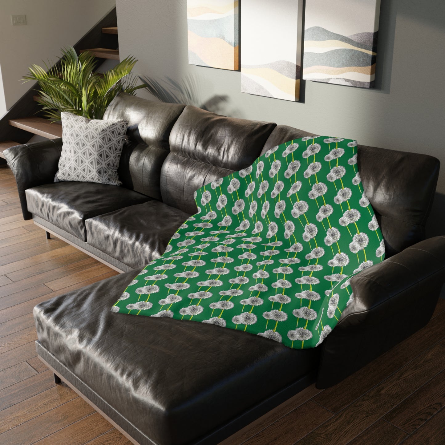 Green blanket with white dandelion print draped over a sofa