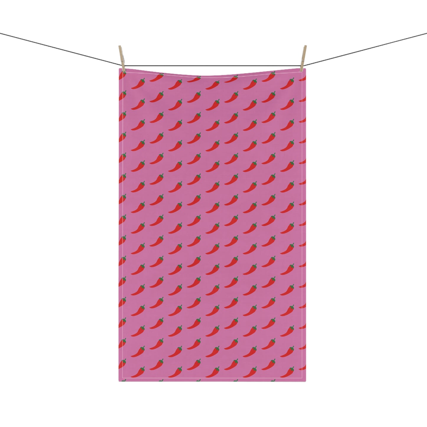 Pink towel with red chili pepper pattern hanging on a line.