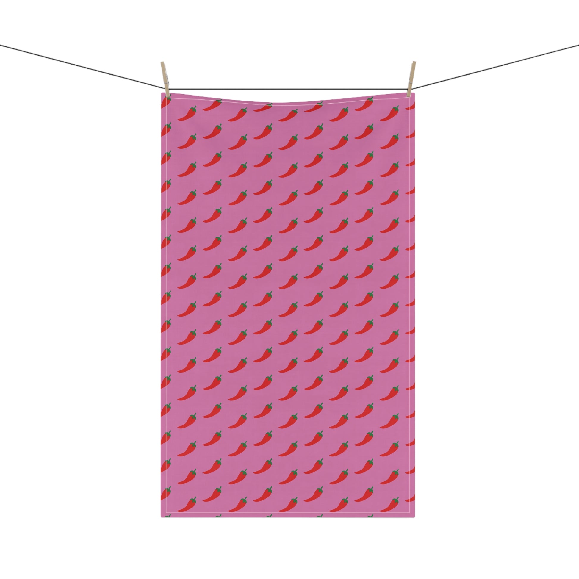 Pink towel with red chili pepper pattern hanging on a line.