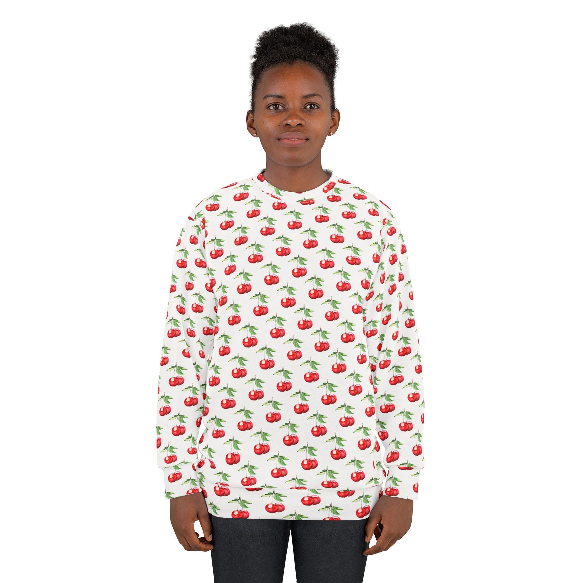 Model wearing a white unisex sweatshirt with a vibrant all-over cherry print, featuring red cherries with green stems.