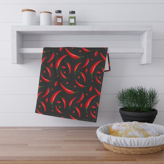 Towel with red chili pepper pattern on a kitchen counter with a plant and basket.