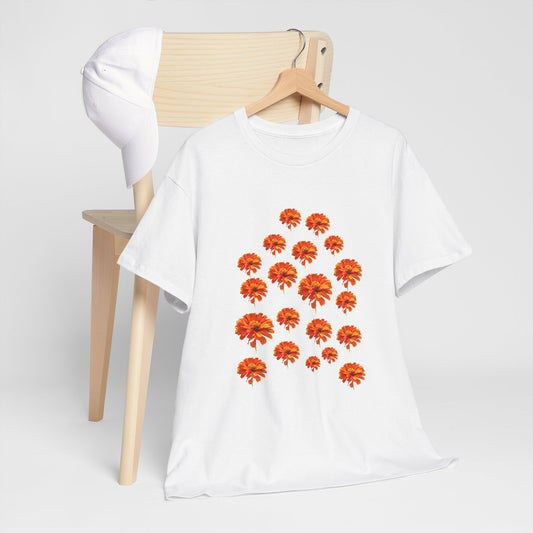 White Zinnia T-Shirt with orange flower design draped on a wooden chair with a white cap on the side