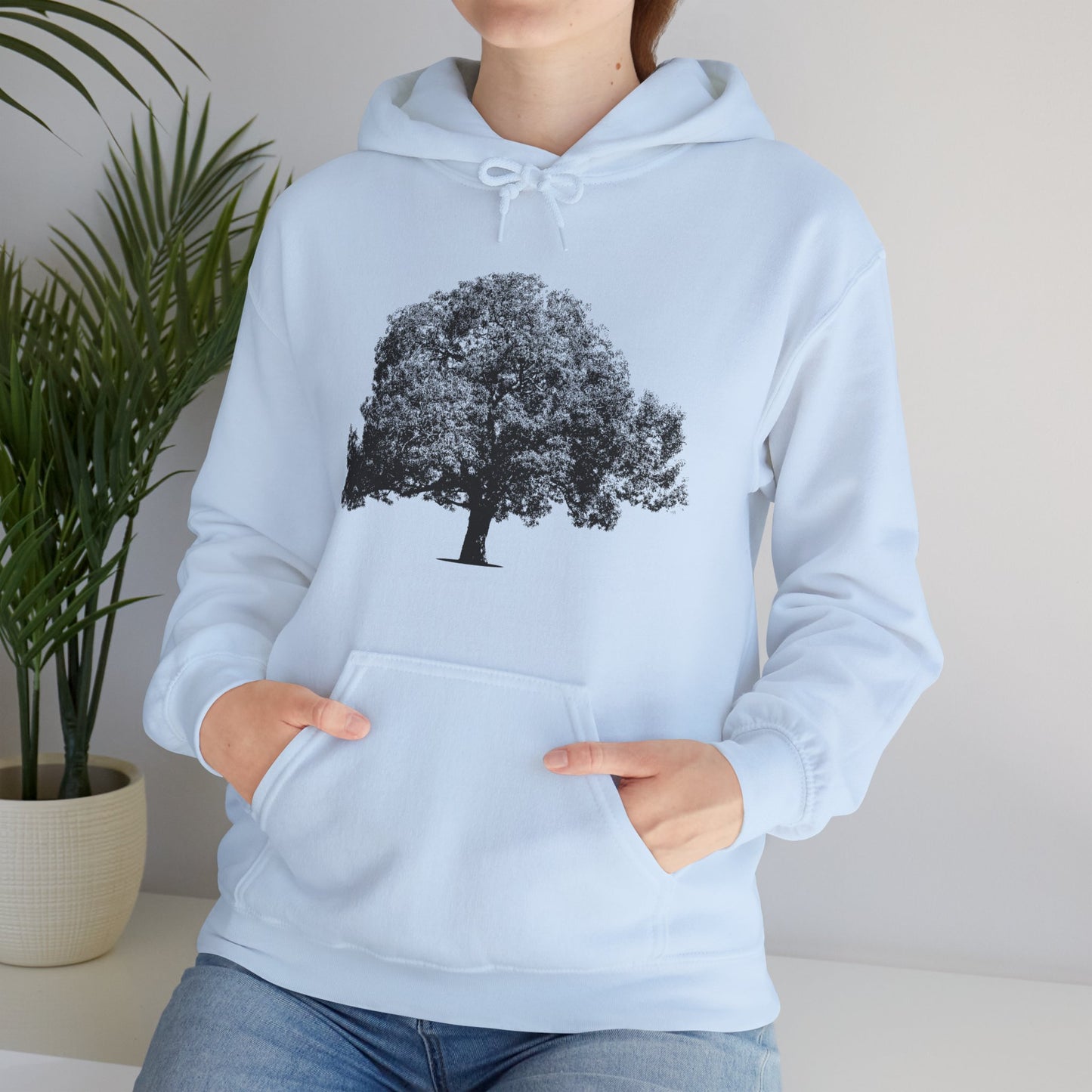 Woman wearing light blue Tree Hoodie with black tree graphic