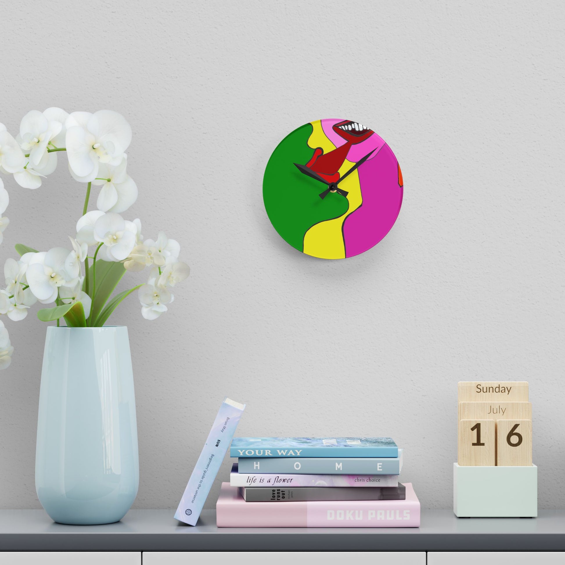 Colorful wall clock on a shelf with a vase, books, and a calendar.