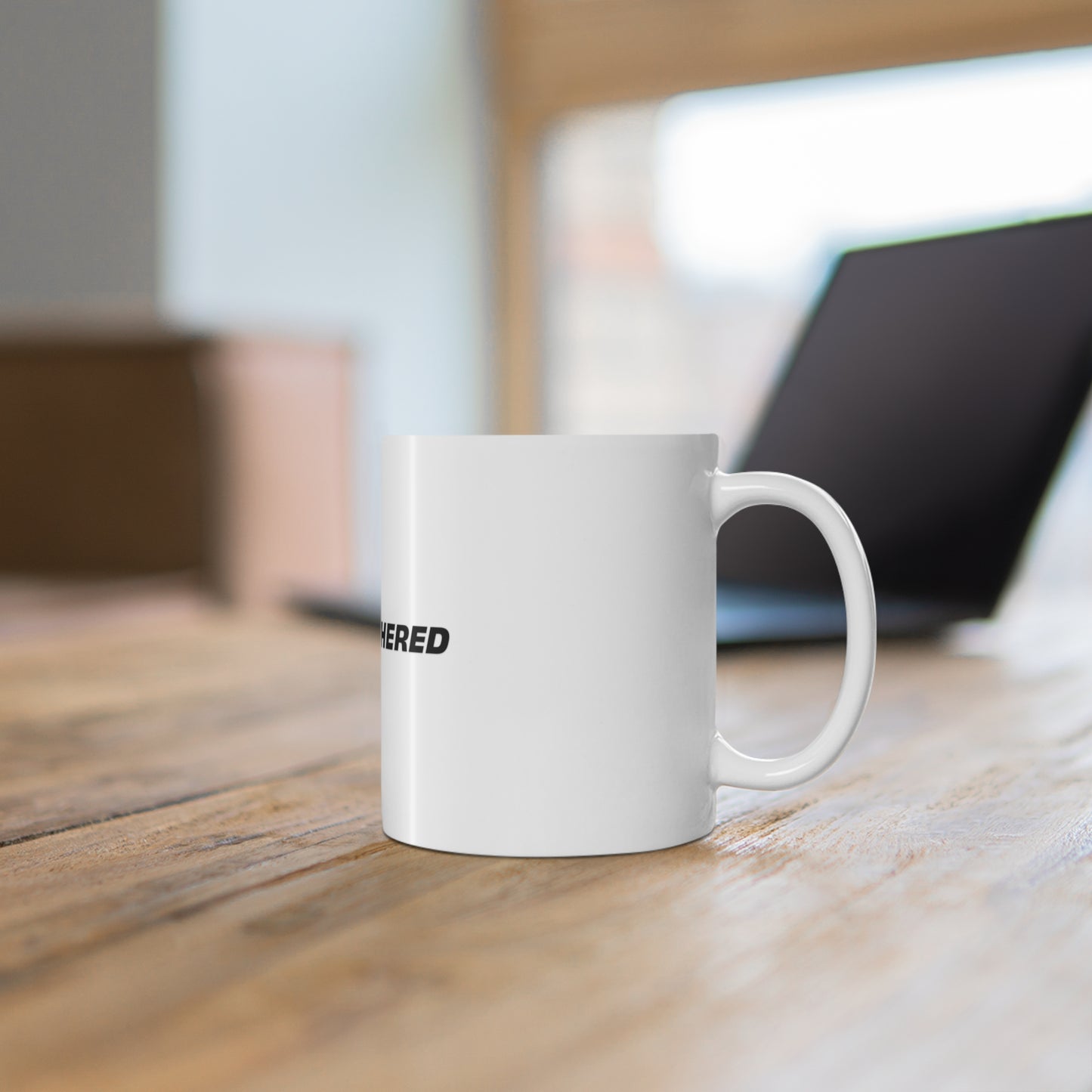 White Stay Unbothered coffee mug on wooden desk workspace setting