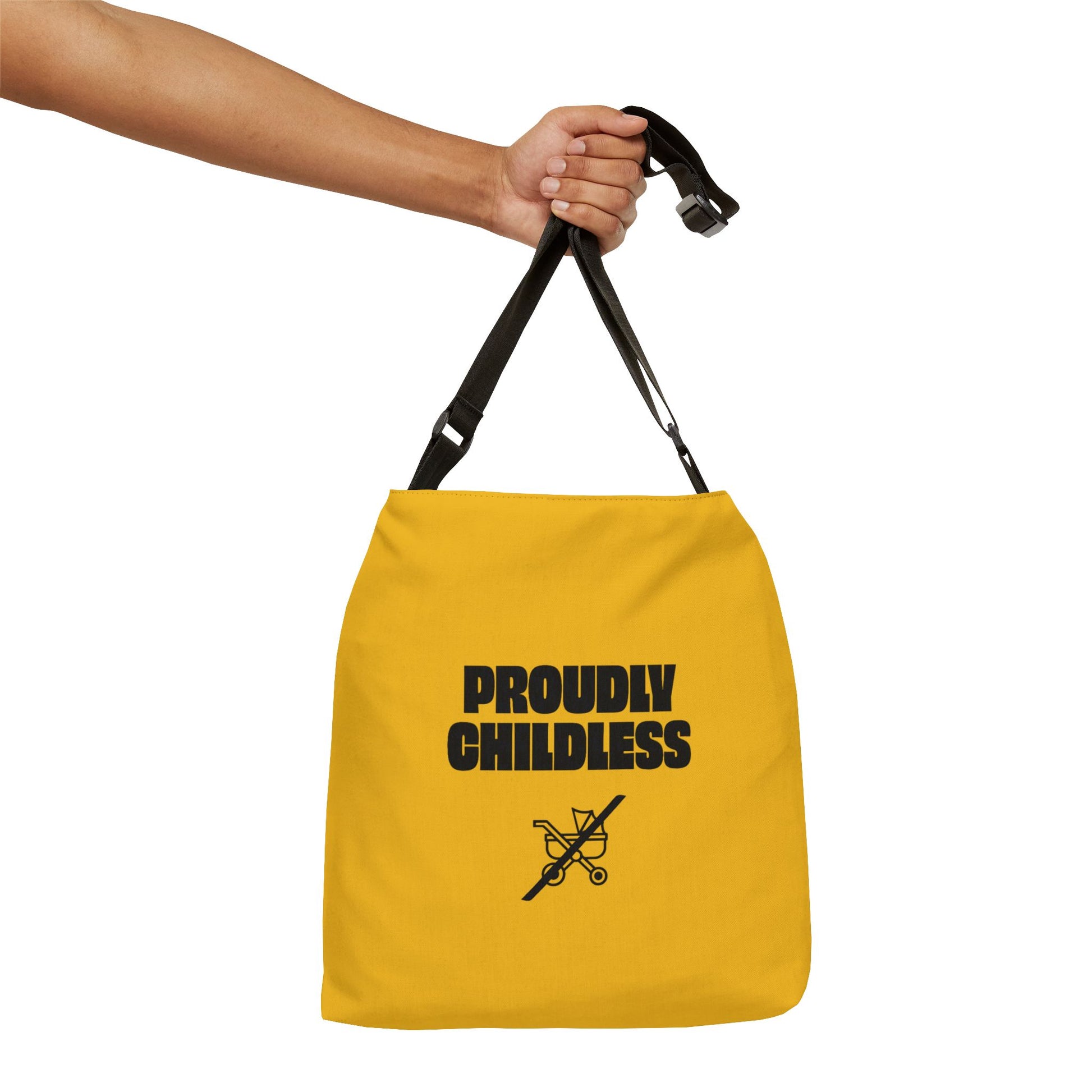 Hand holding Proudly Childless Adjustable Tote Bag by black straps against white background