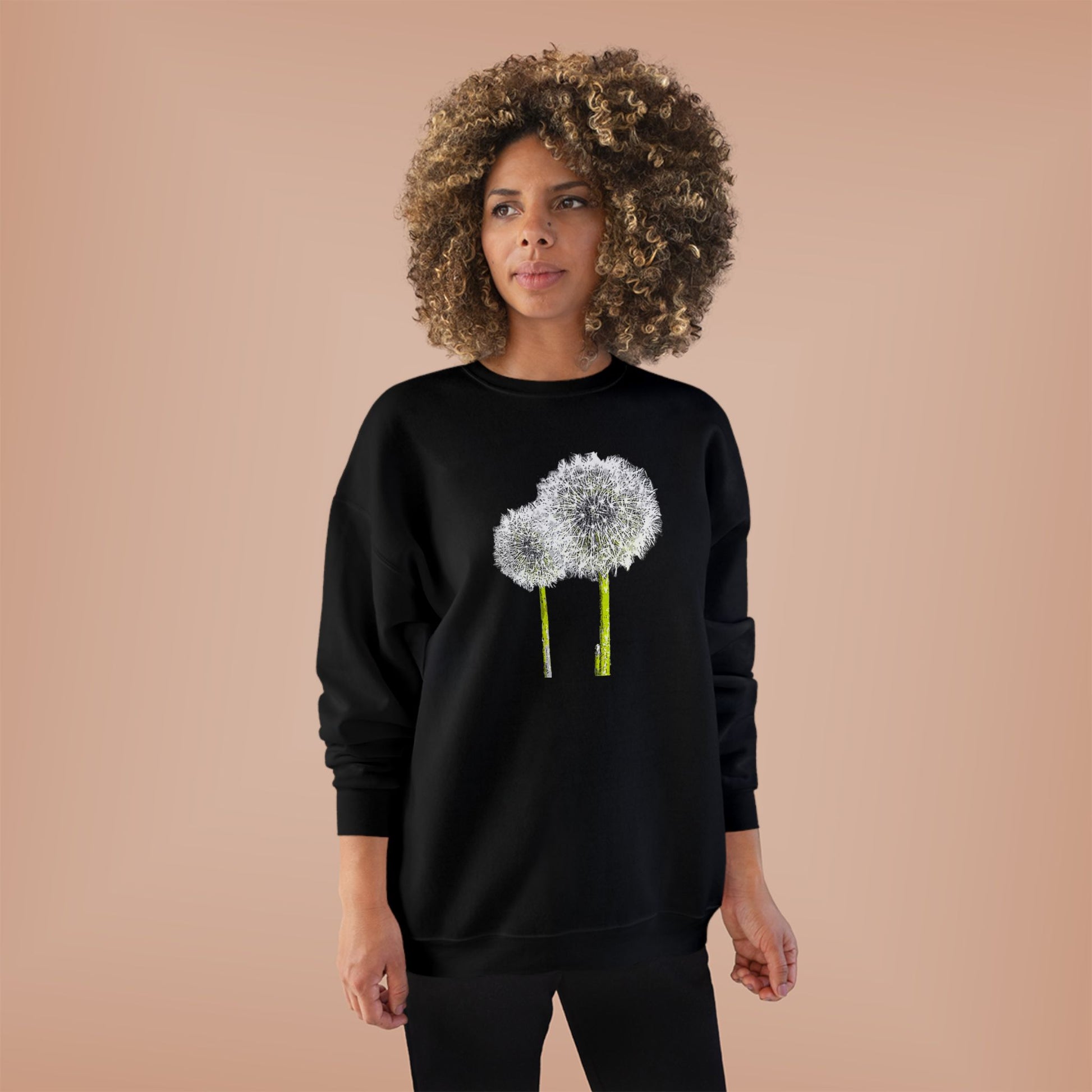 Woman in black Tantrum Media Dandelion Unisex Sweatshirt with white dandelion print, peach background