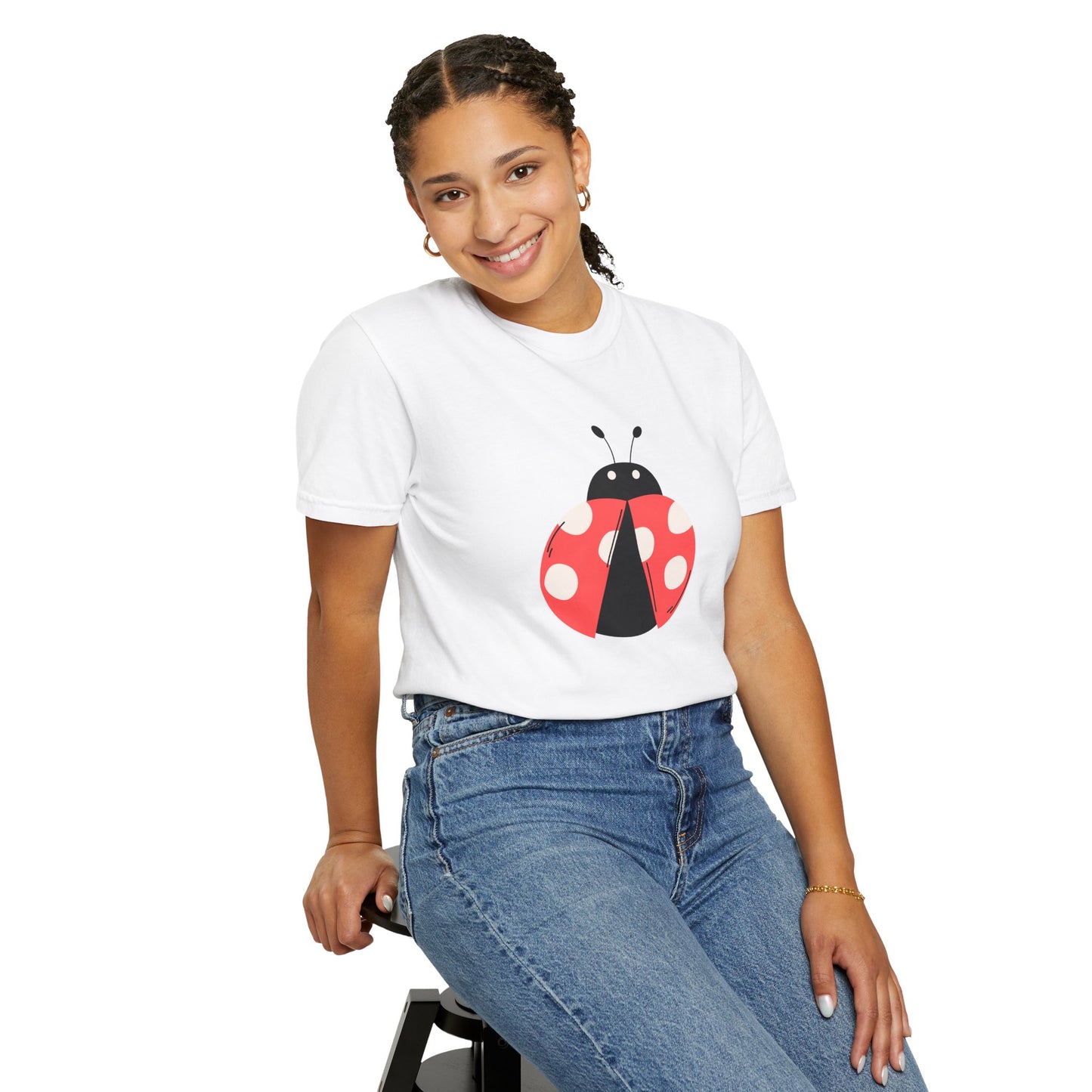 Woman wearing white Lady Bug T-Shirt with lady bug design while sitting.