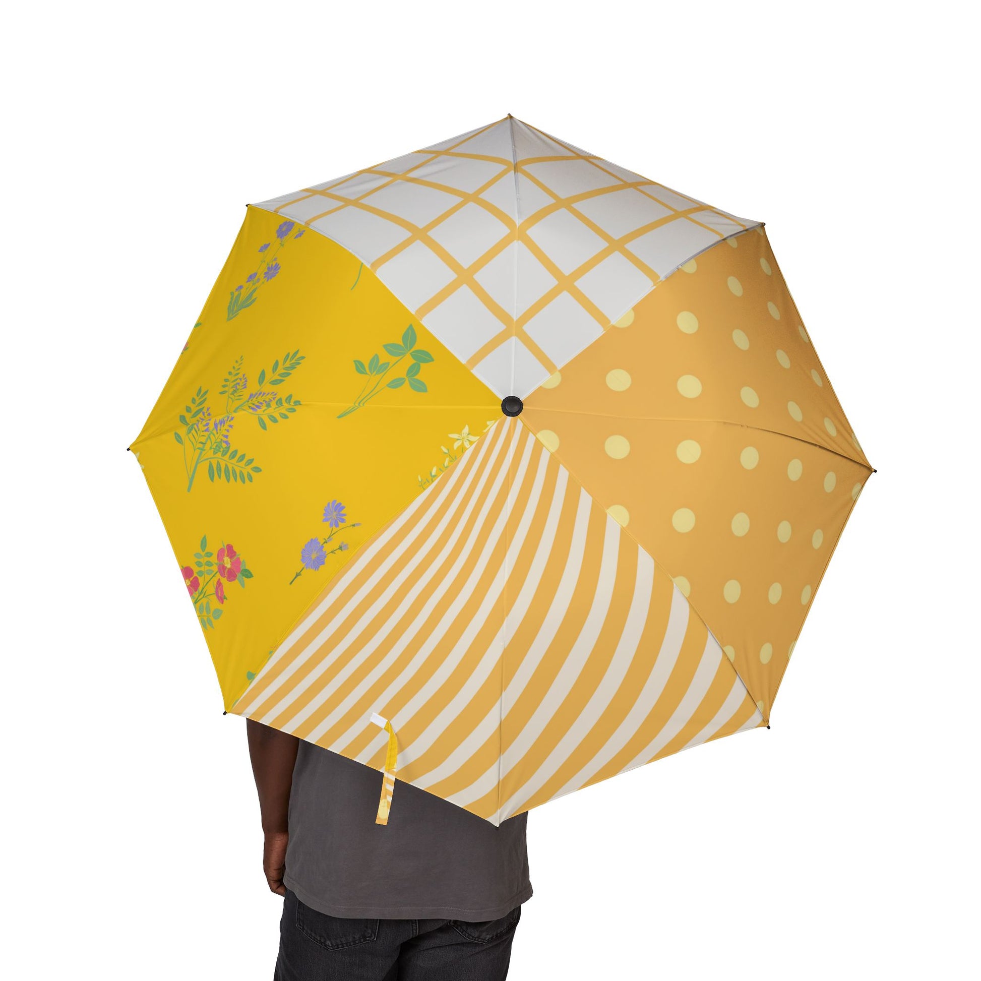 Person holding colorful patchwork umbrella with polka dots, stripes, florals, and grid patterns.