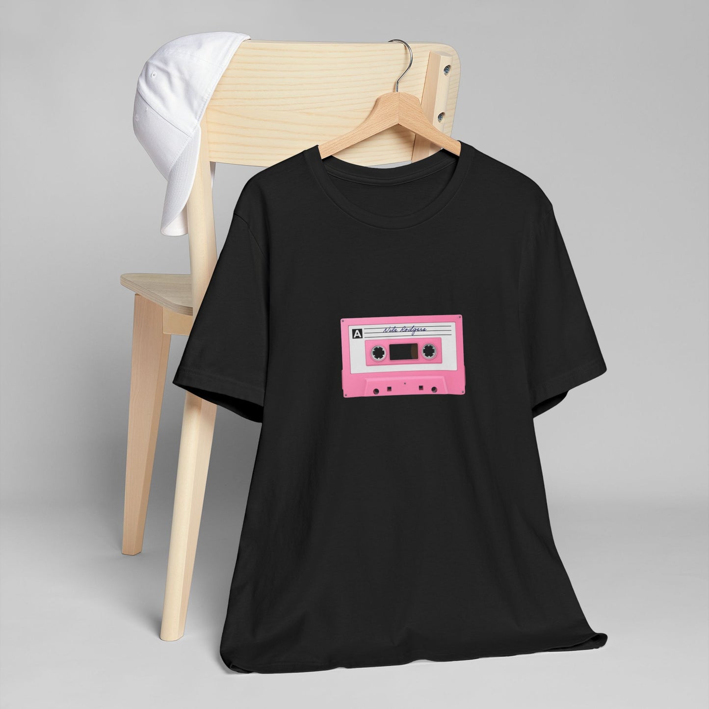 Black t-shirt with a pink cassette tape graphic on a gray background