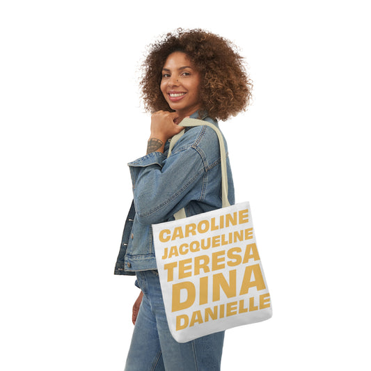 Woman carrying a white tote bag featuring the names Caroline, Jacqueline, Teresa, Dina, and Danielle in bold beige text