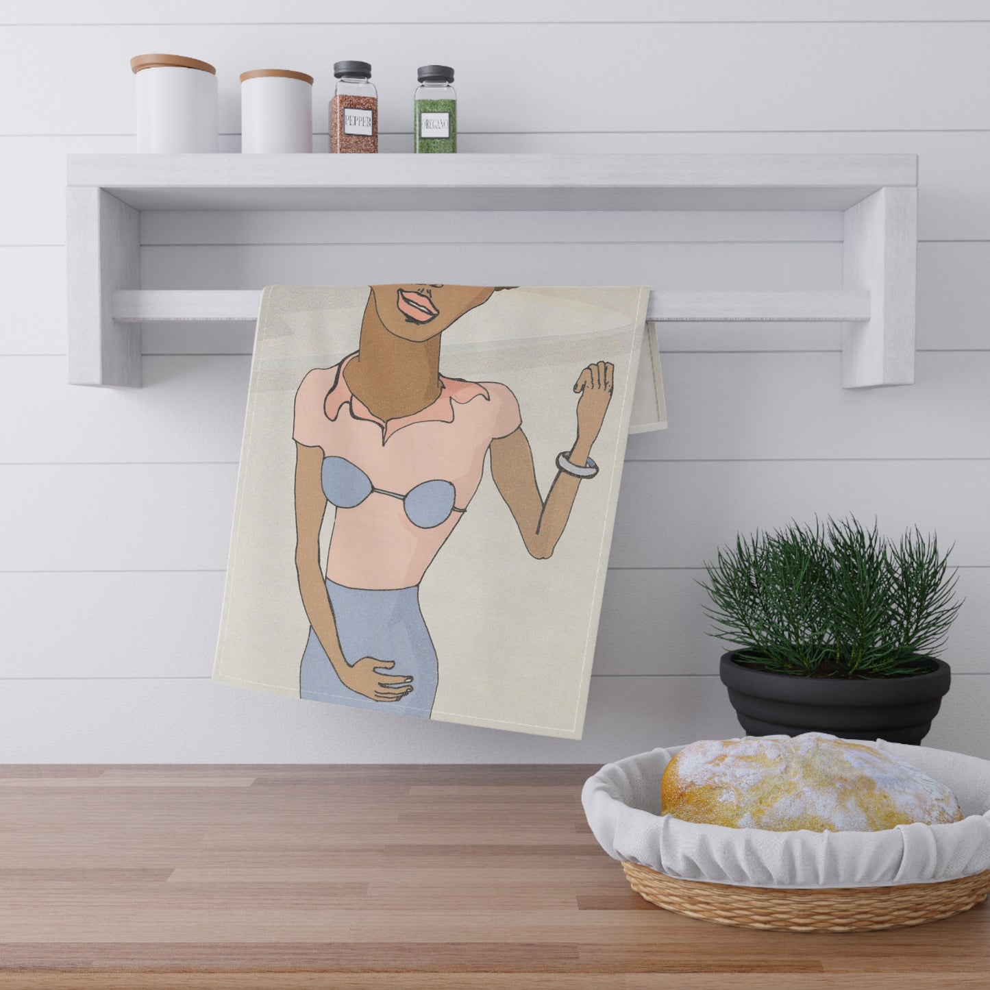 Morenita Kitchen Towel draped over a white kitchen shelf near bowls, herbs, and condiments.