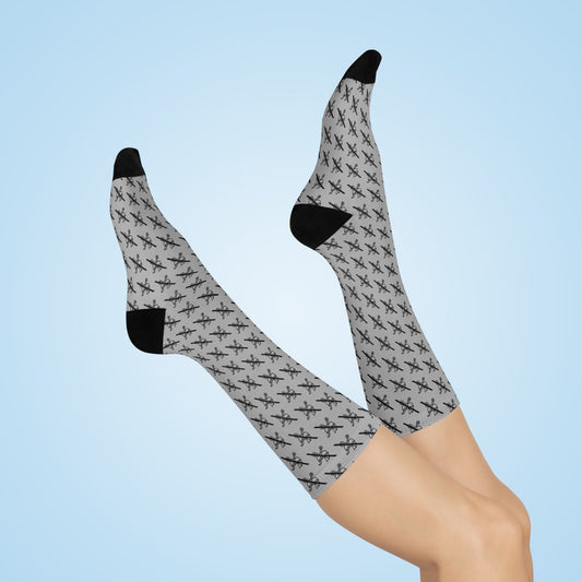 Grey Proudly Childless crew socks with black heel and toe shown on crossed legs against light blue background
