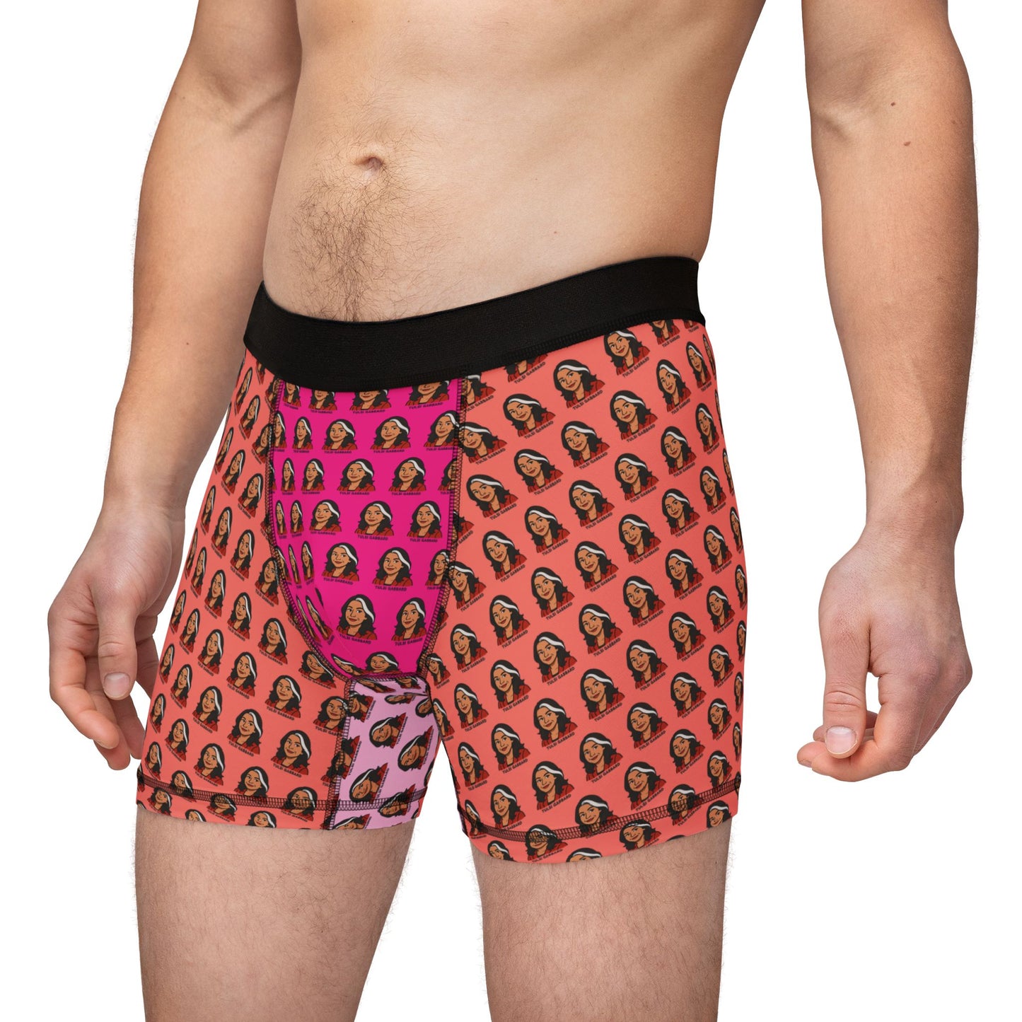 Male model wearing Tulsi Gabbard boxer briefs with orange and pink face print and black waistband, front-side view