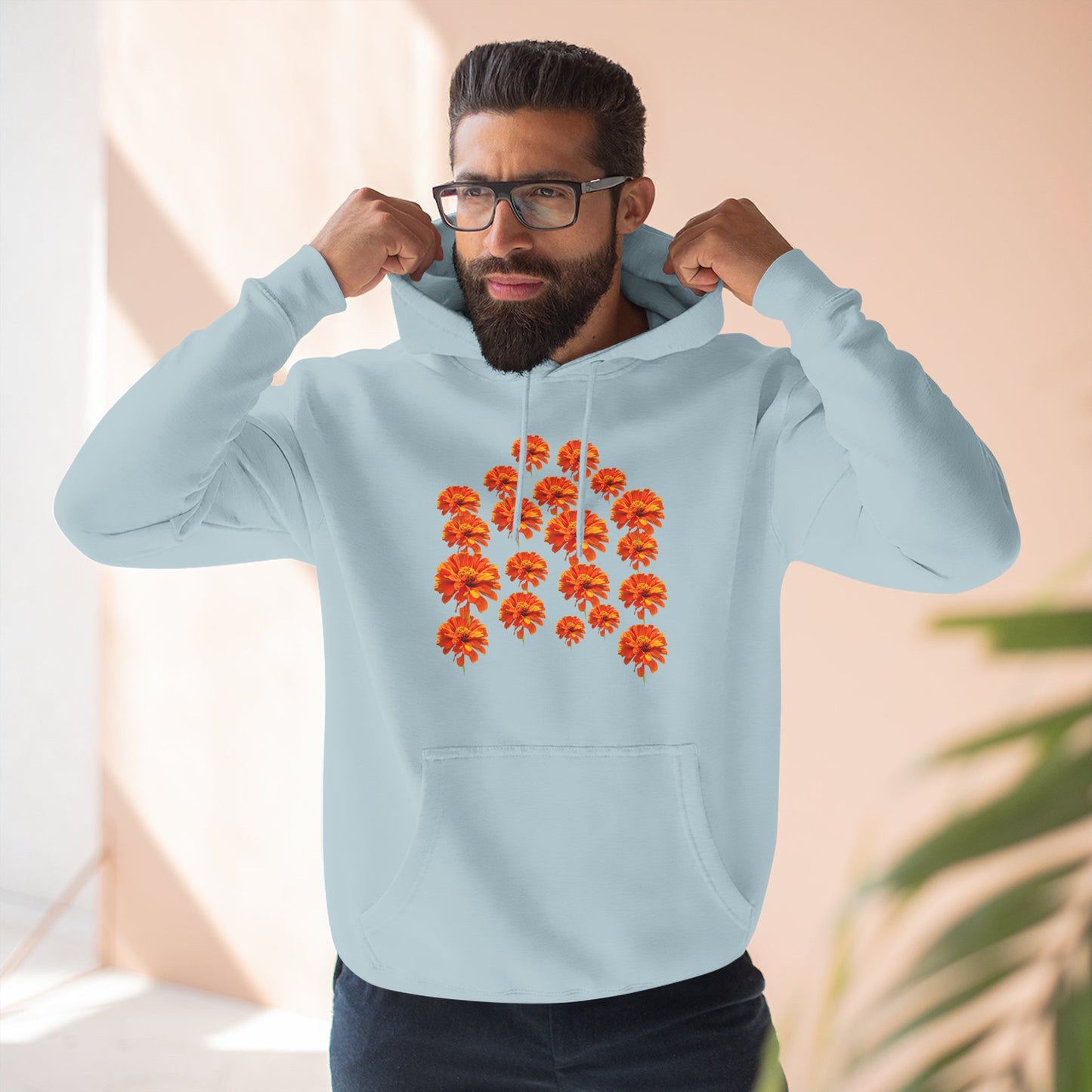 Man wearing light blue Zinnia Hoodie adjusting hood indoors