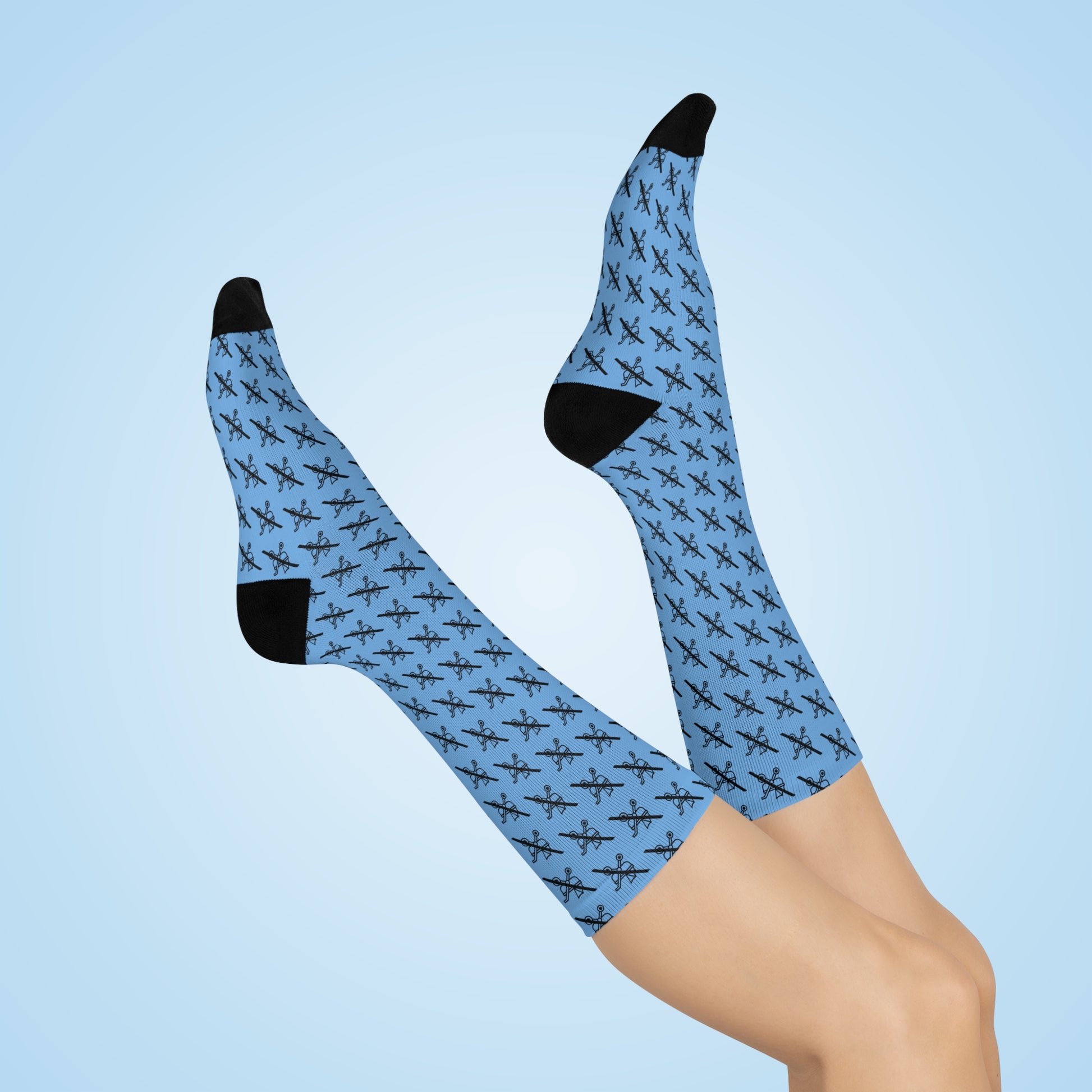 Blue Proudly Childless crew socks with black heel and toe shown on crossed legs against light blue background
