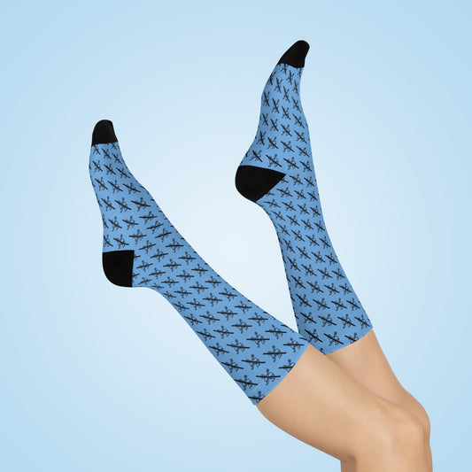 Blue Proudly Childless crew socks with black heel and toe shown on crossed legs against light blue background