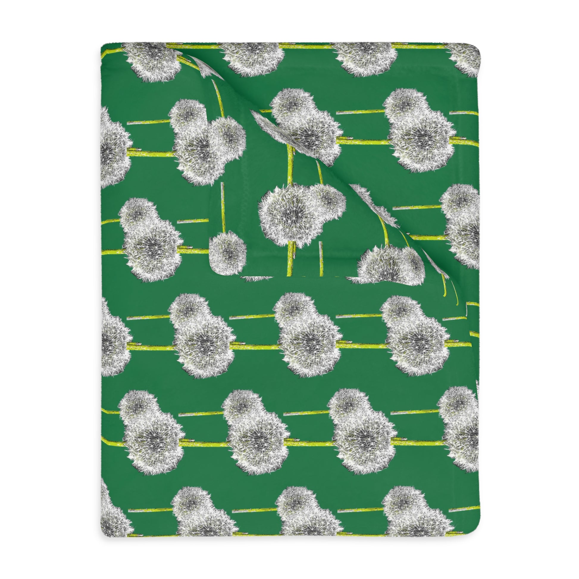 Close-up of folded green blanket showing white dandelion pattern
