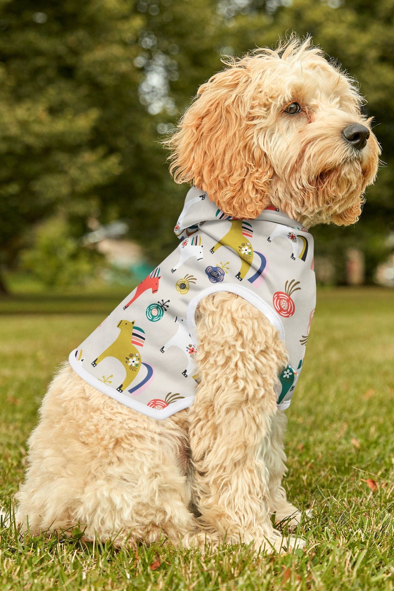 Dog wearing horse print pet hoodie sitting outdoors three quarter view