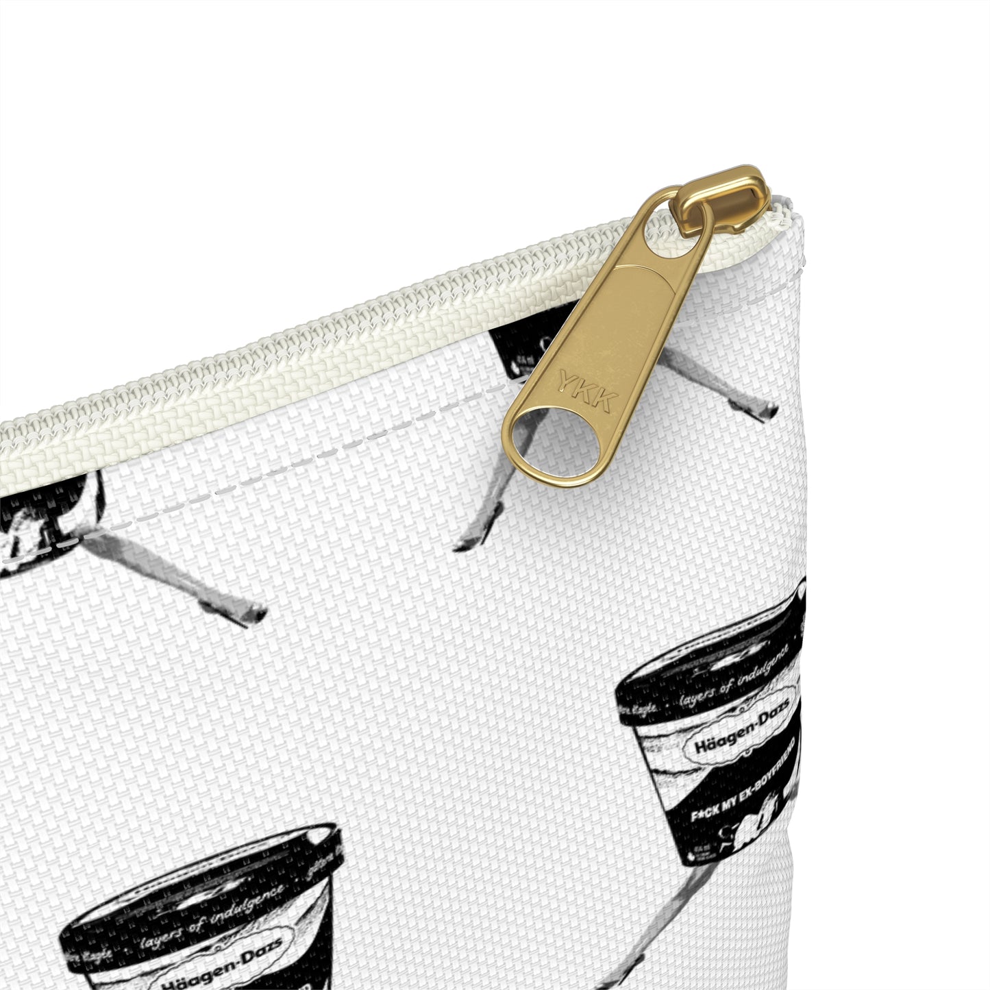 Close-up of a white pouch with black and white patterned design and gold zipper pull.