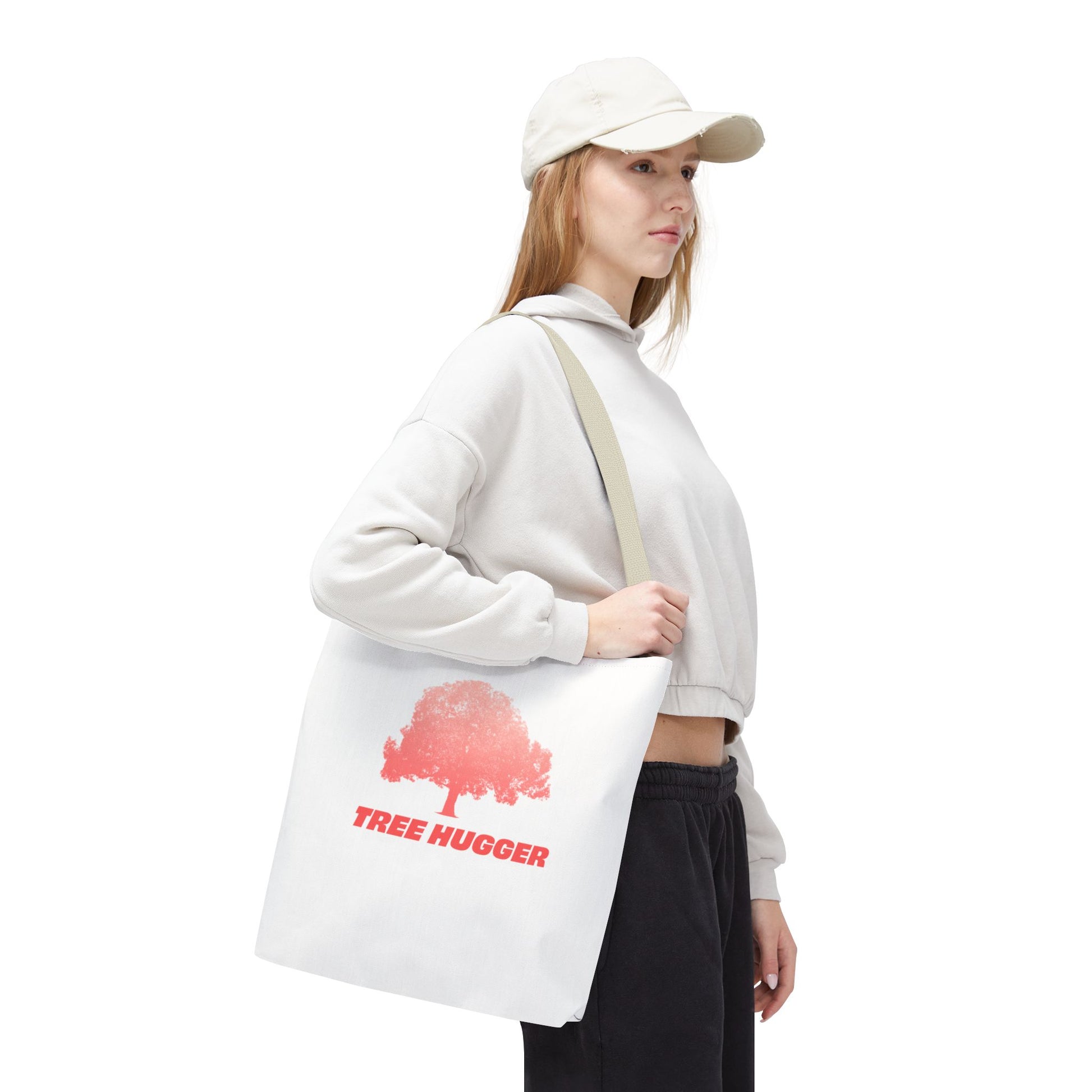 Woman wearing cap carrying Tree Hugger Tote Bag with red tree graphic, side view