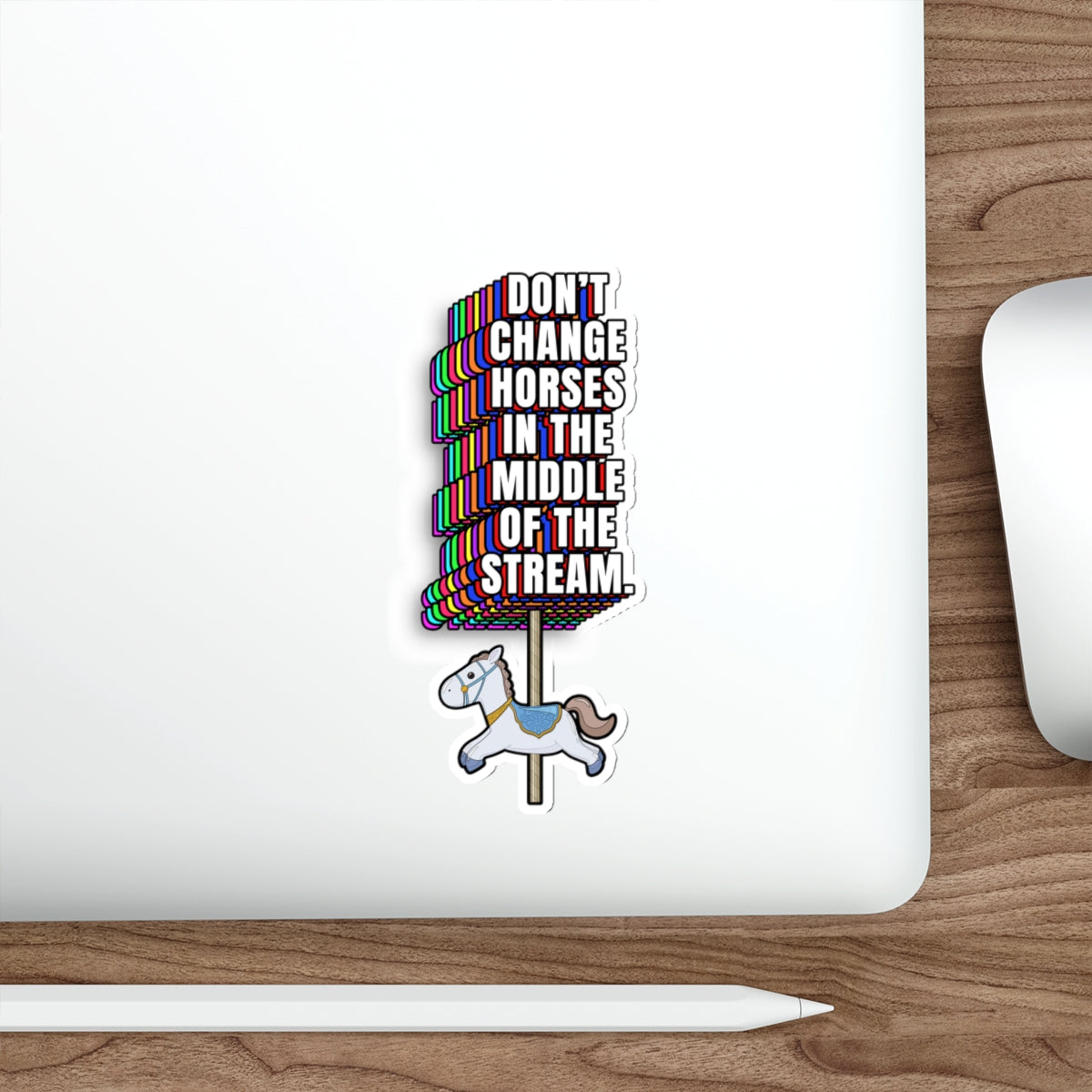 Laptop on desk with Don’t Change Horses in the Middle of the Stream sticker near trackpad
