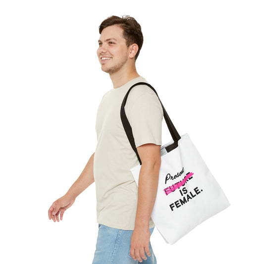 Man smiling while carrying a white tote bag with the phrase "Present is Female" and "Future" crossed out in pink