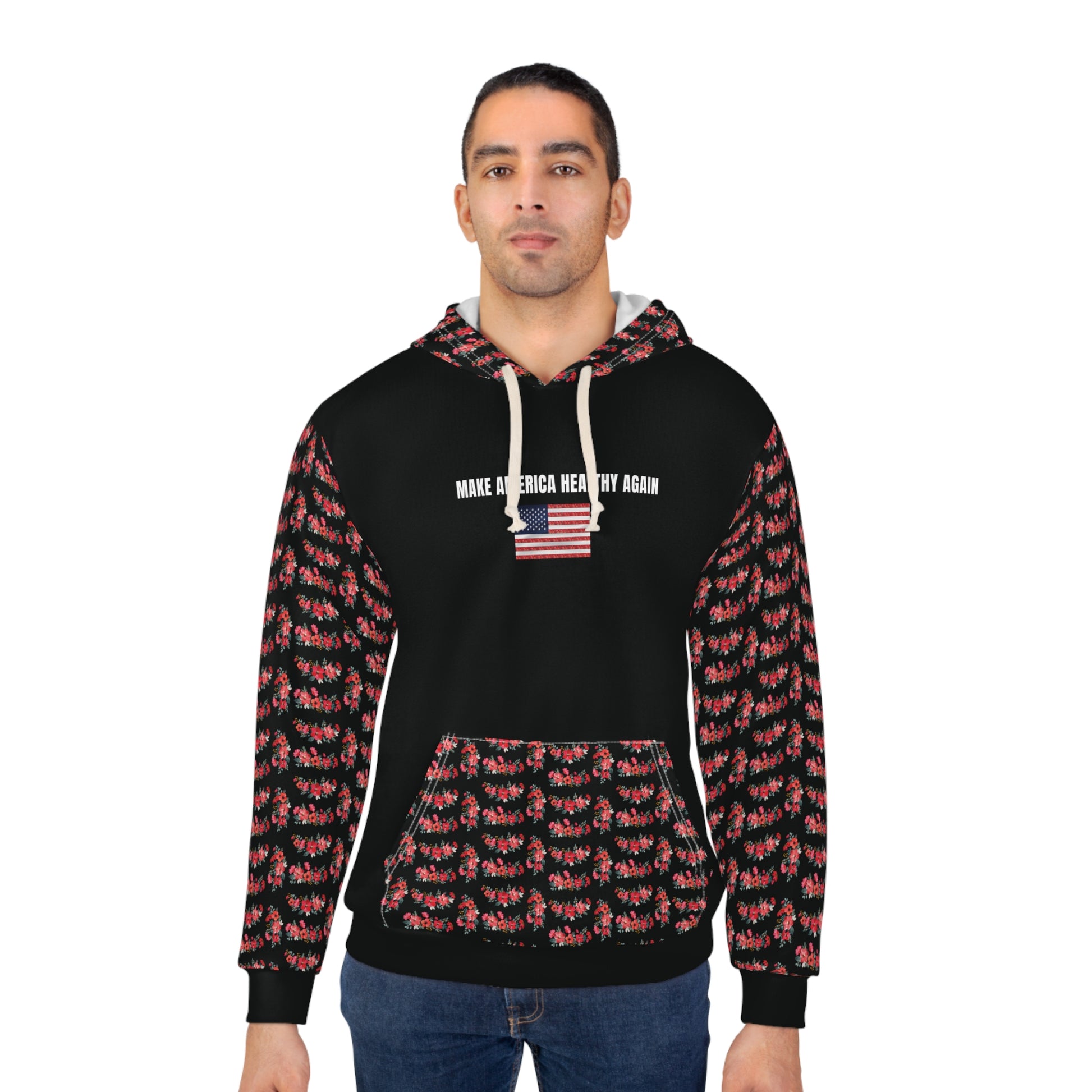 A person wearing a black unisex hoodie with the phrase "Make America Healthy Again" above an American flag graphic, featuring red floral patterned sleeves and front pocket, standing against a white background.