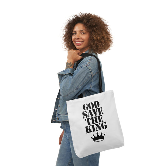 Woman carrying a white tote bag featuring bold black text "GOD SAVE THE KING" with a crown graphic underneath