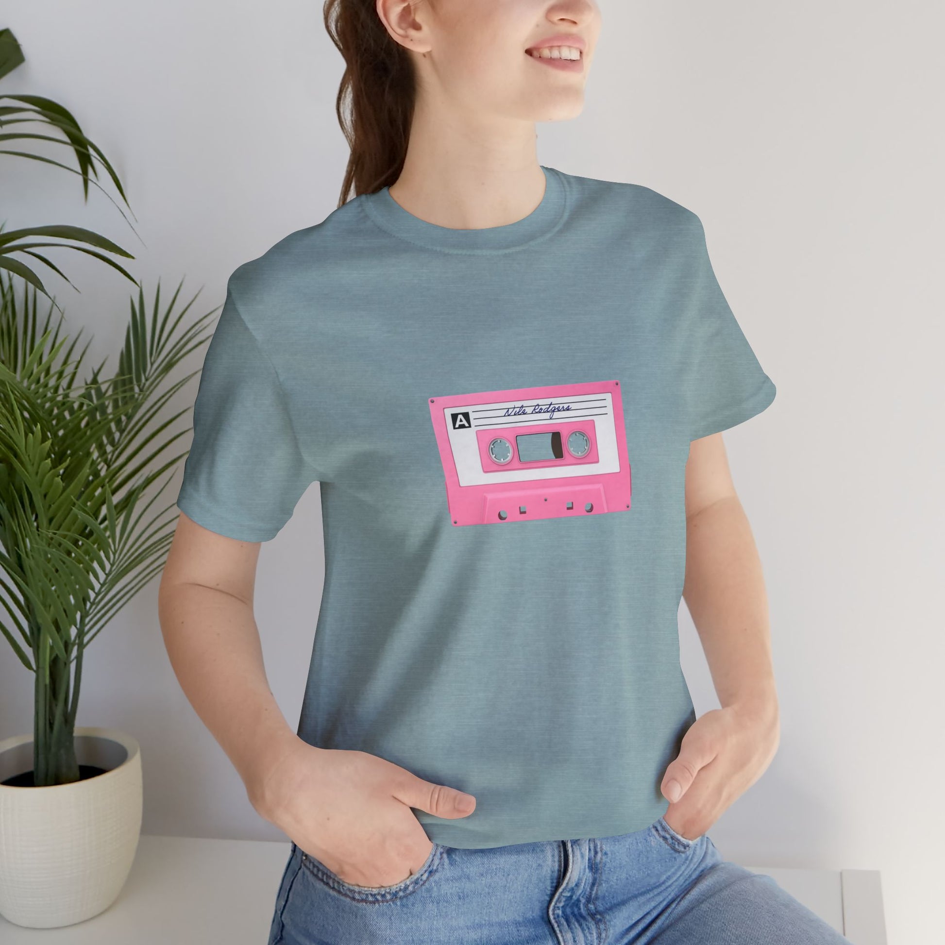 Person wearing a blue t-shirt with a pink cassette tape graphic