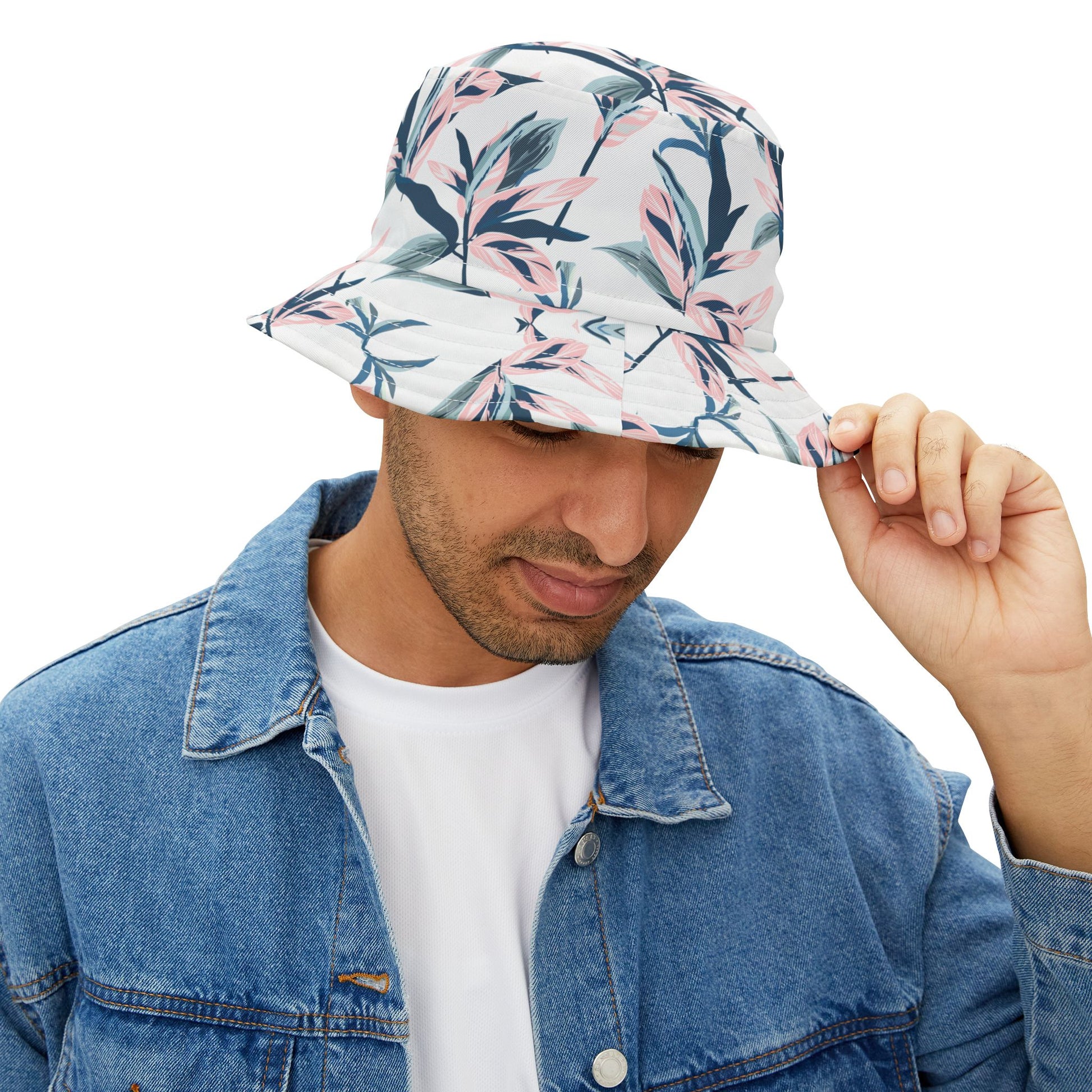Man wearing floral bucket hat with watercolor blossom design, holding brim while looking down.