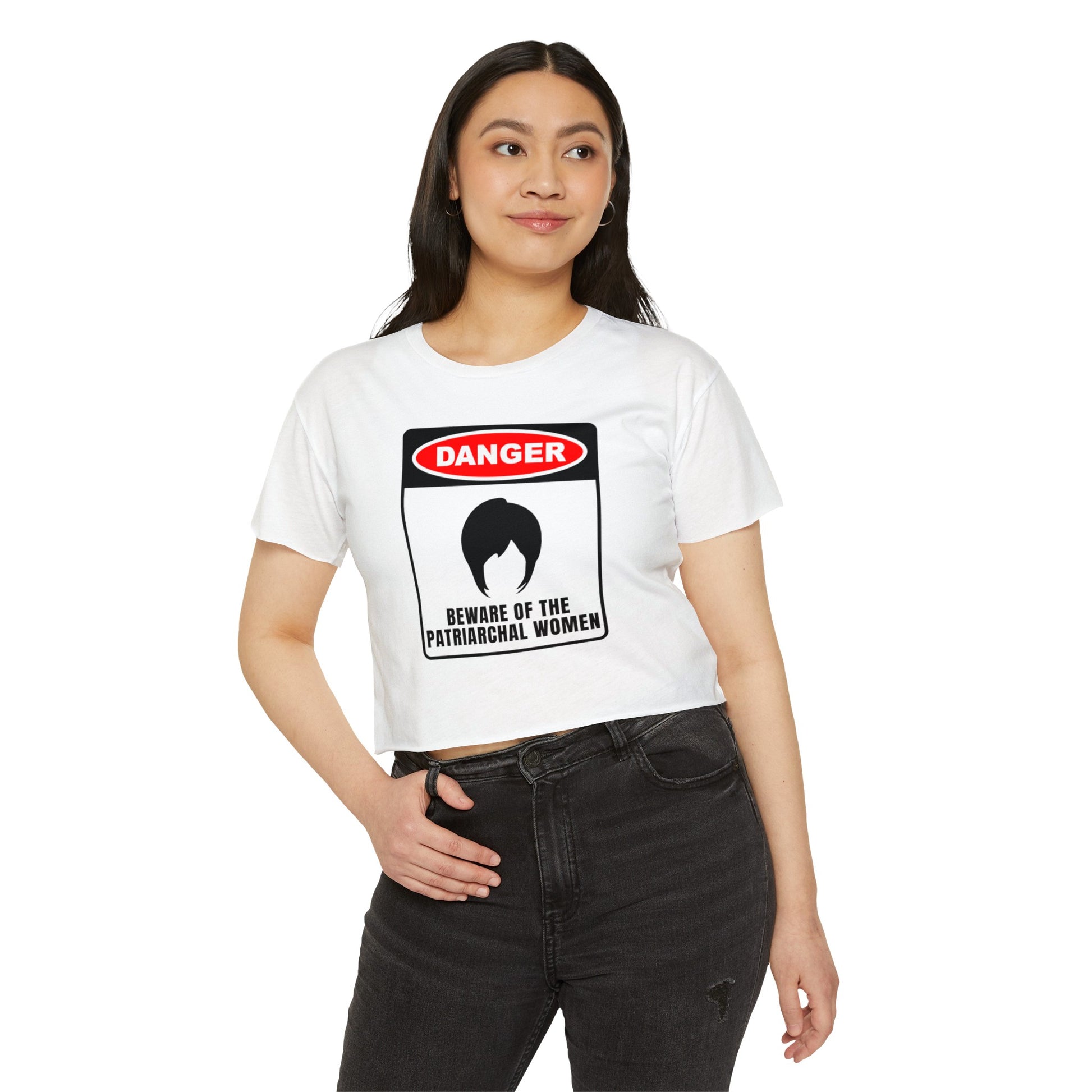 Woman wearing a white crop top with a bold “Danger: Beware of the Patriarchal Women” graphic featuring a silhouette of a woman's hairstyle.