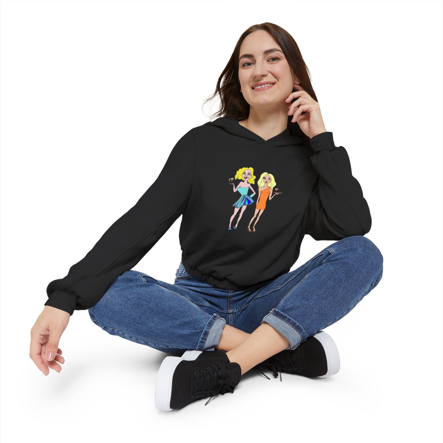 Woman sitting cross-legged in black waitress hand-drawn hoodie, smiling.