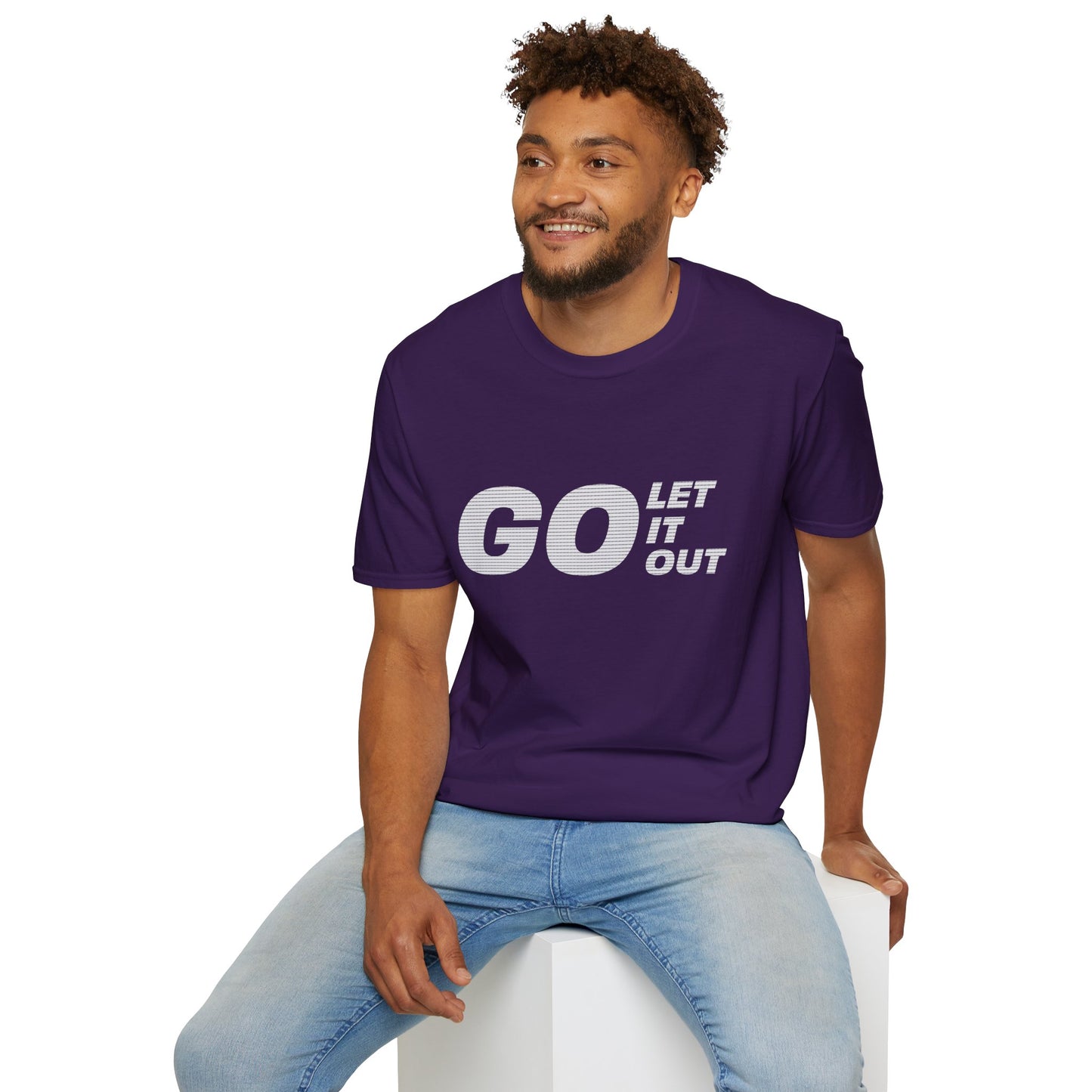 Man wearing a purple t-shirt with 'GO LET IT OUT' text, sitting on a white stool against a white background