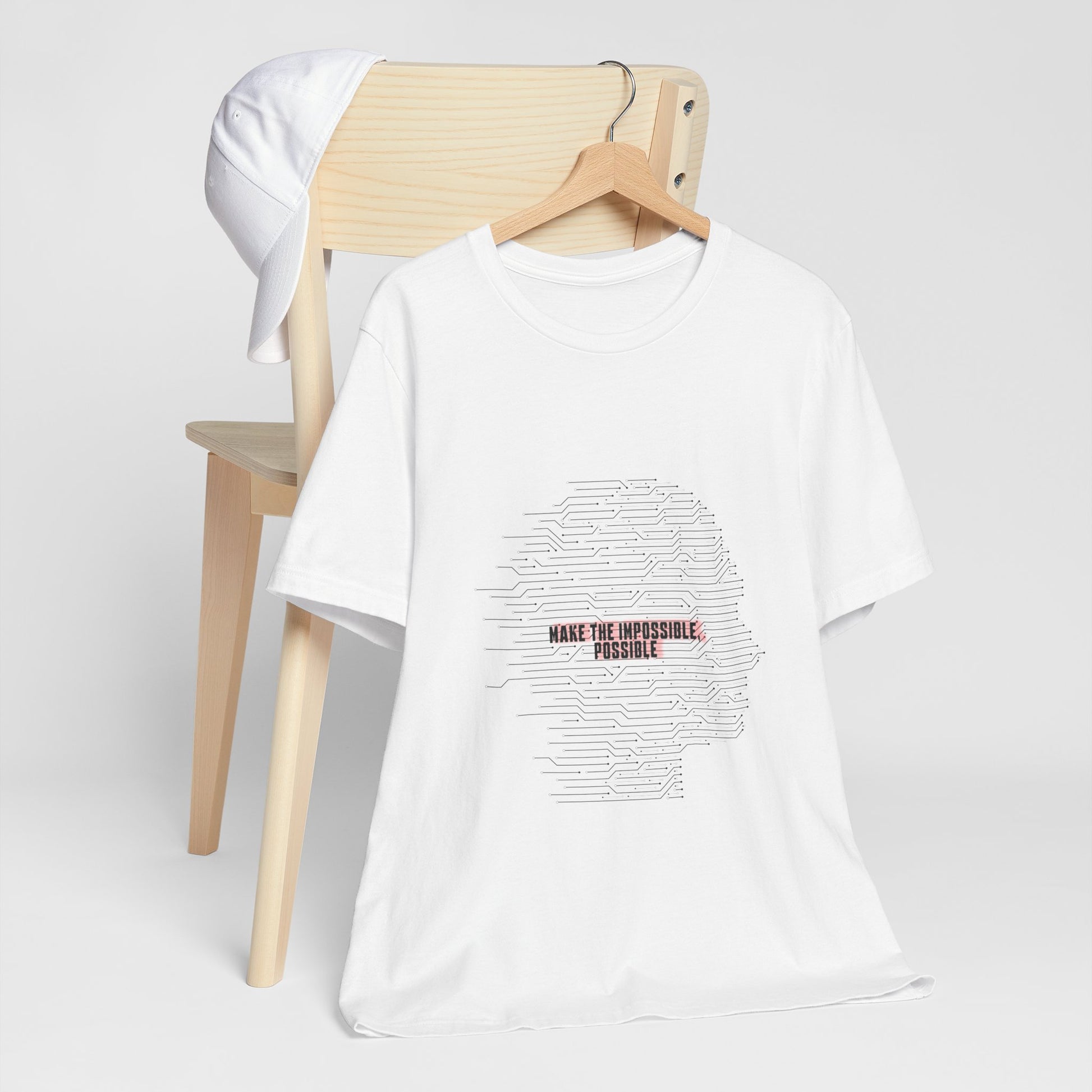 White Make It Possible T-Shirt on chair with empowering design.