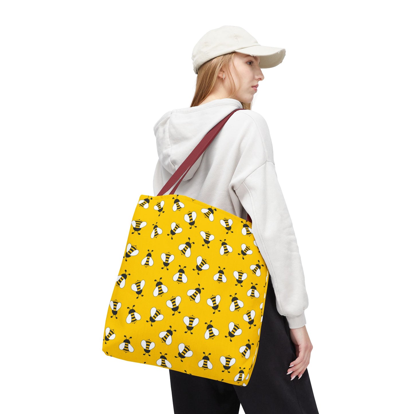 Person carrying a yellow tote bag with bee pattern on a white background