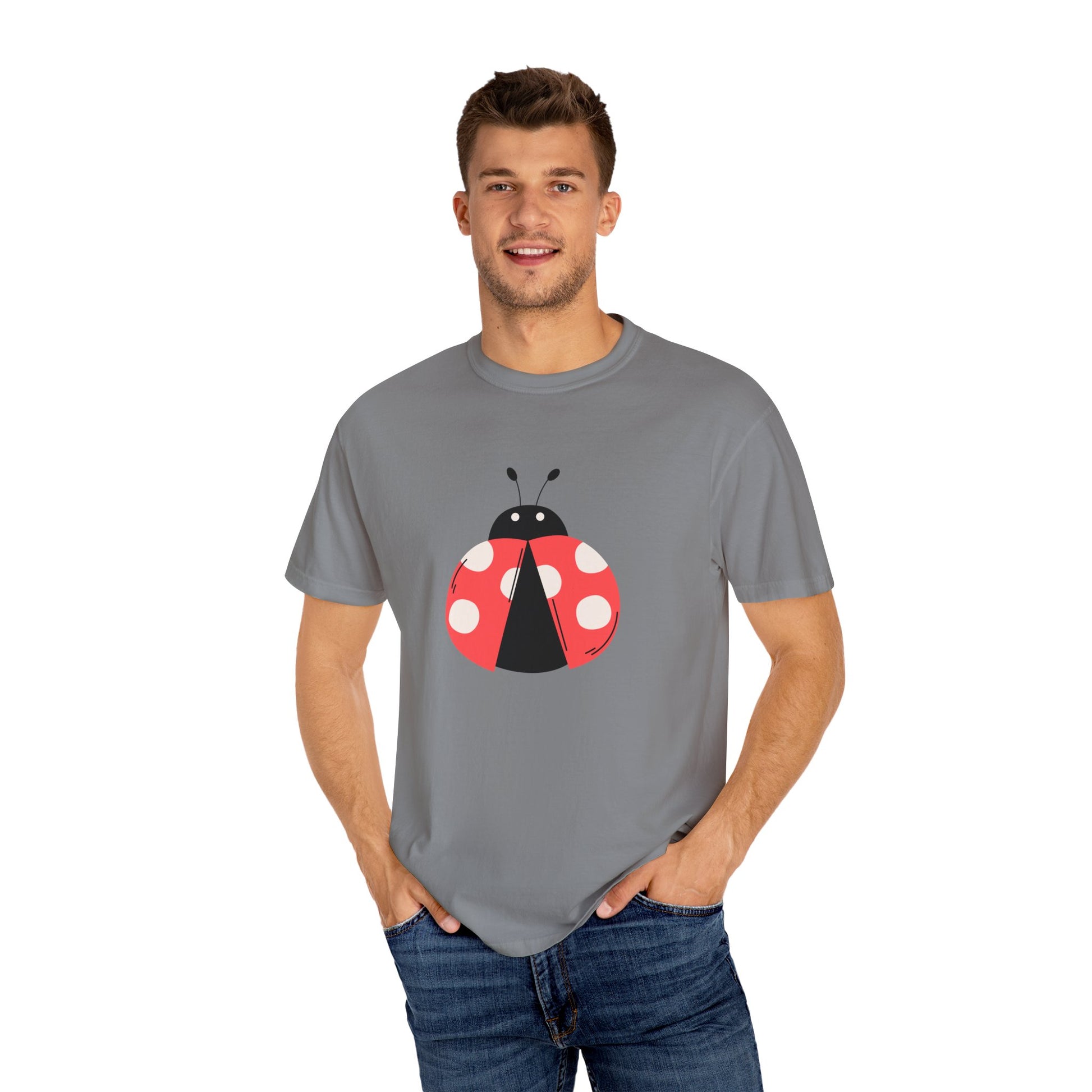 Man in gray Lady Bug T-Shirt with lady bug design, hands in pockets.