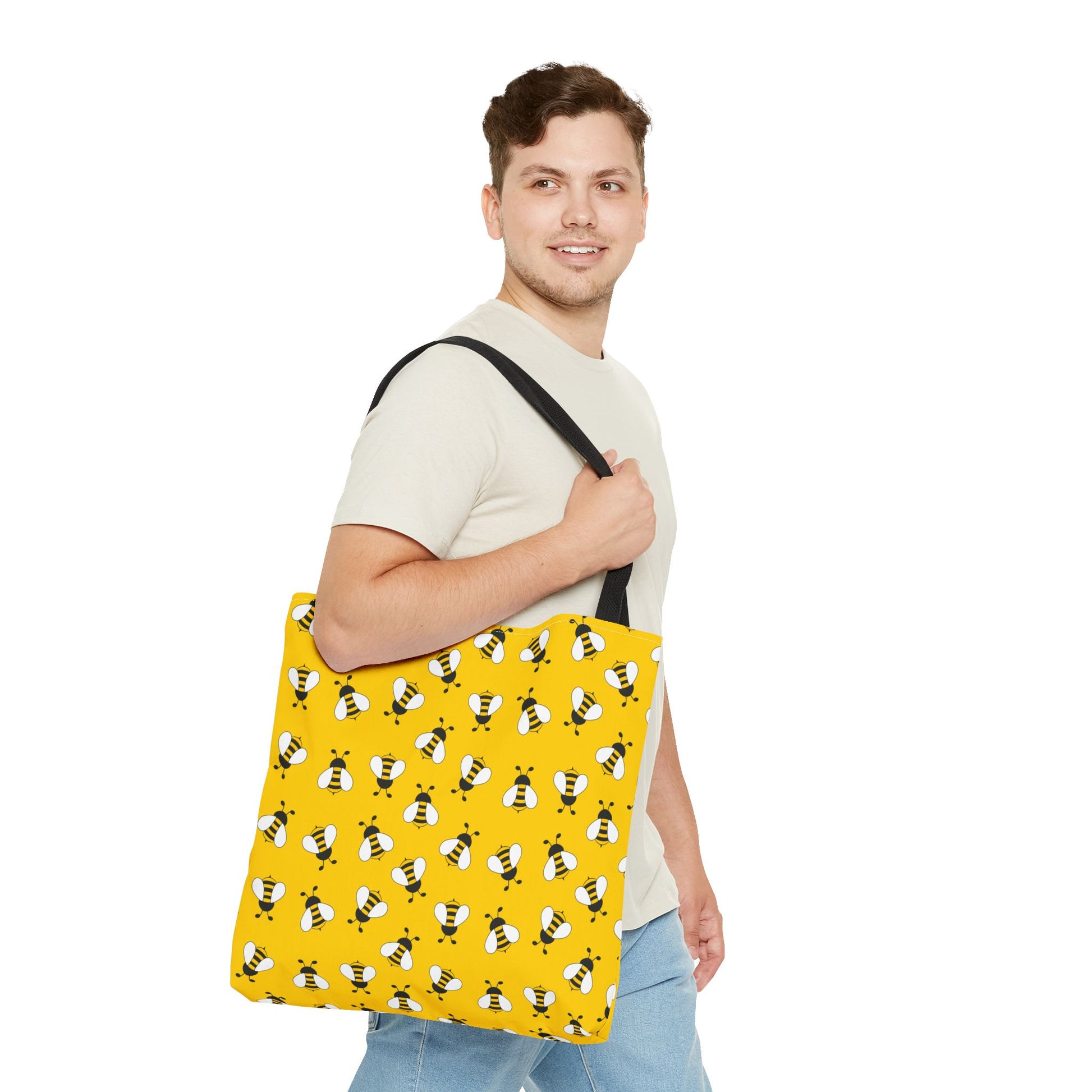 Man holding a yellow tote bag with bee pattern on a white background
