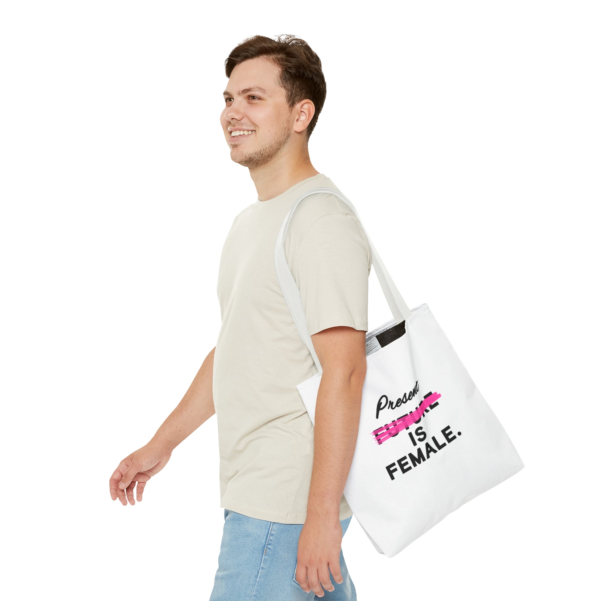 Man smiling while carrying a white tote bag with the phrase "Present is Female" and "Future" crossed out in pink