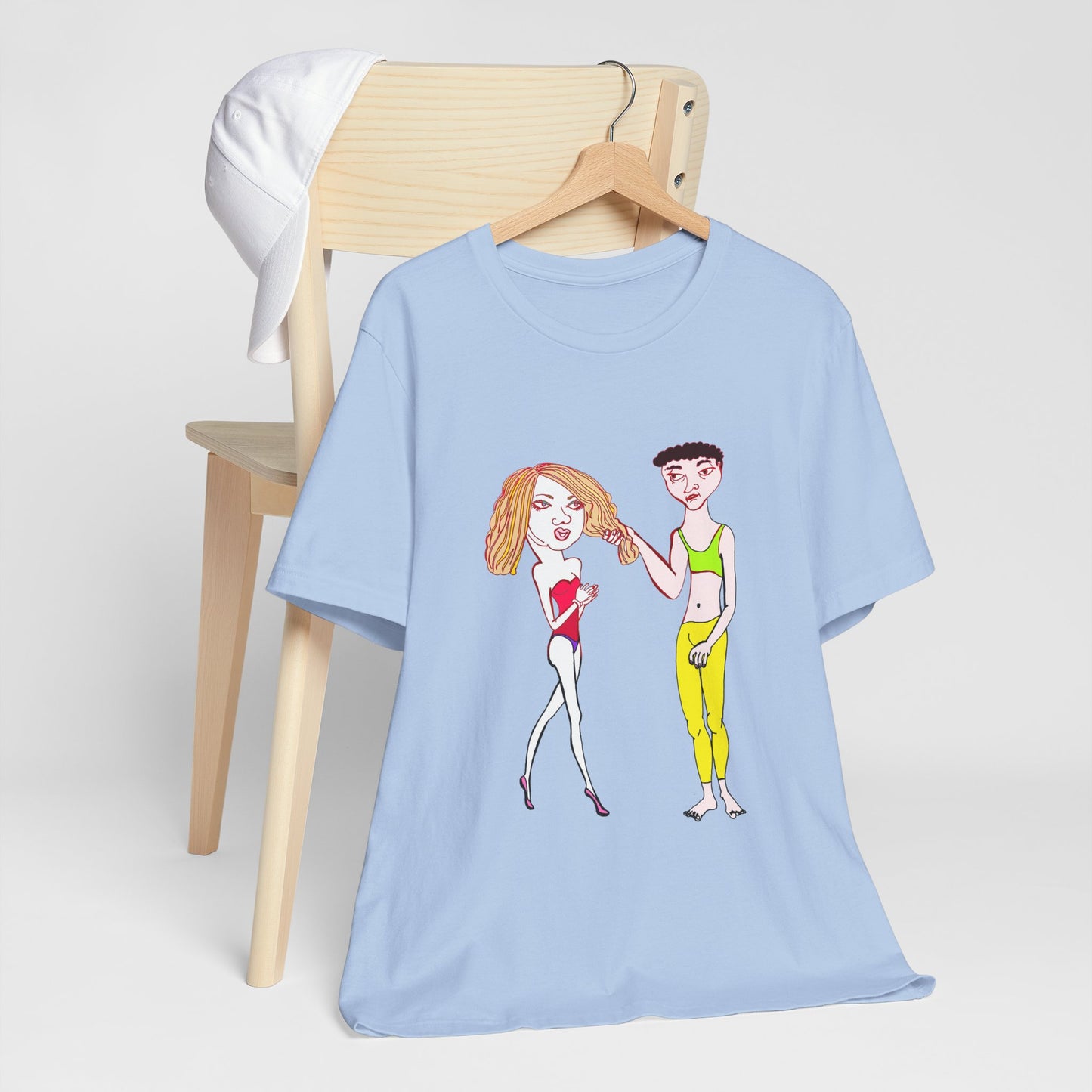 Charlotte and Van hand-drawn couple tee in blue draped over a chair with a white cloth, styled for a soft lifestyle look.