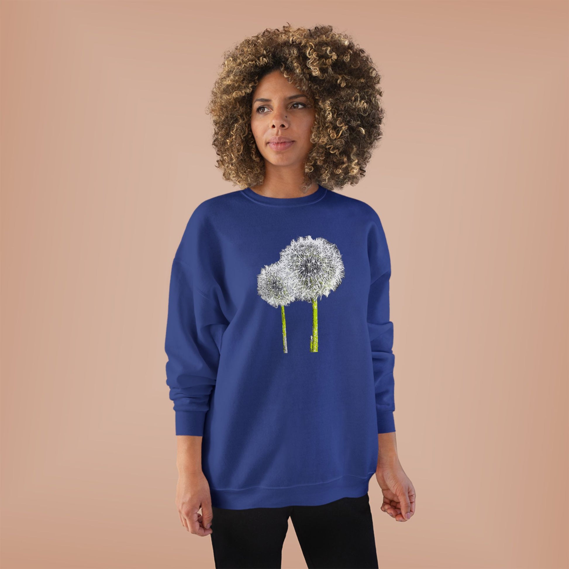 Woman in blue Tantrum Media Dandelion Unisex Sweatshirt with white dandelion print, peach background