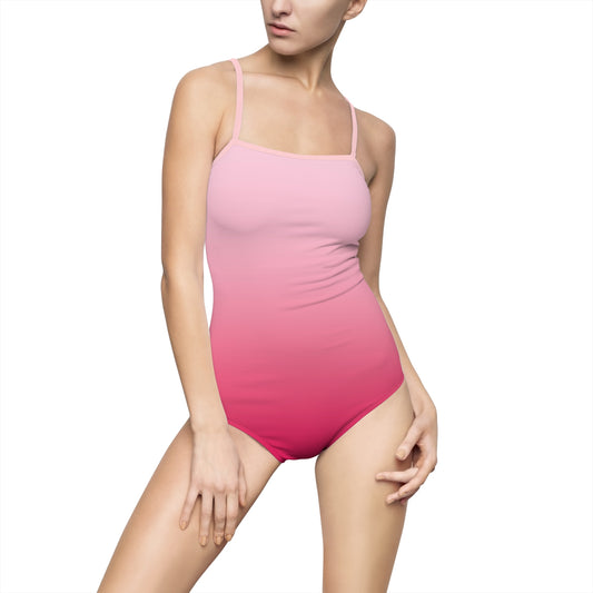 Woman wearing a one-piece swimsuit with a soft pink ombré gradient, thin shoulder straps, and a sleek, minimalist design.