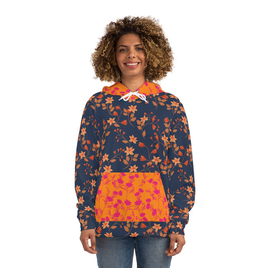 A person wearing a navy blue hoodie with an all-over orange floral pattern, featuring a contrasting bright orange front pocket with pink floral print, and white drawstrings, standing against a white background.