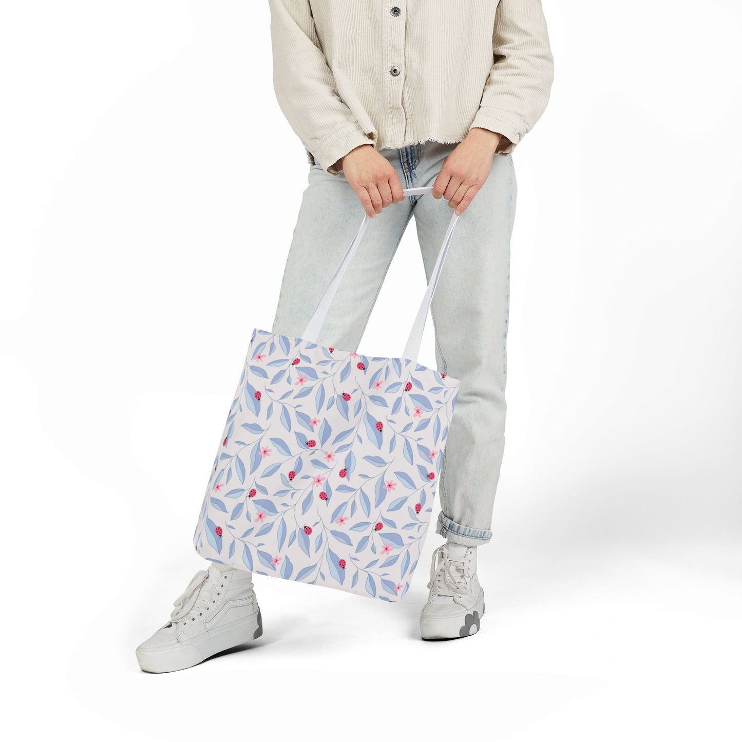 Person holding a Lady Bug Garden Tote Bag against white background.