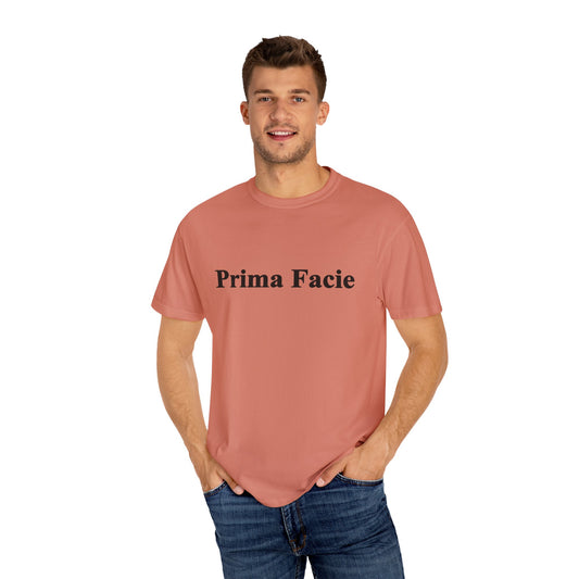 Man wearing a coral Prima Facie T-Shirt with black text, made from 100% US-grown cotton.
