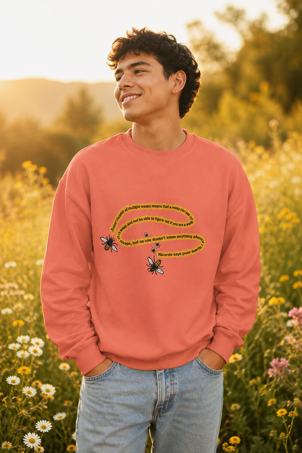 Man wearing a peach bumblebee sweatshirt in a golden wildflower and daisy field.