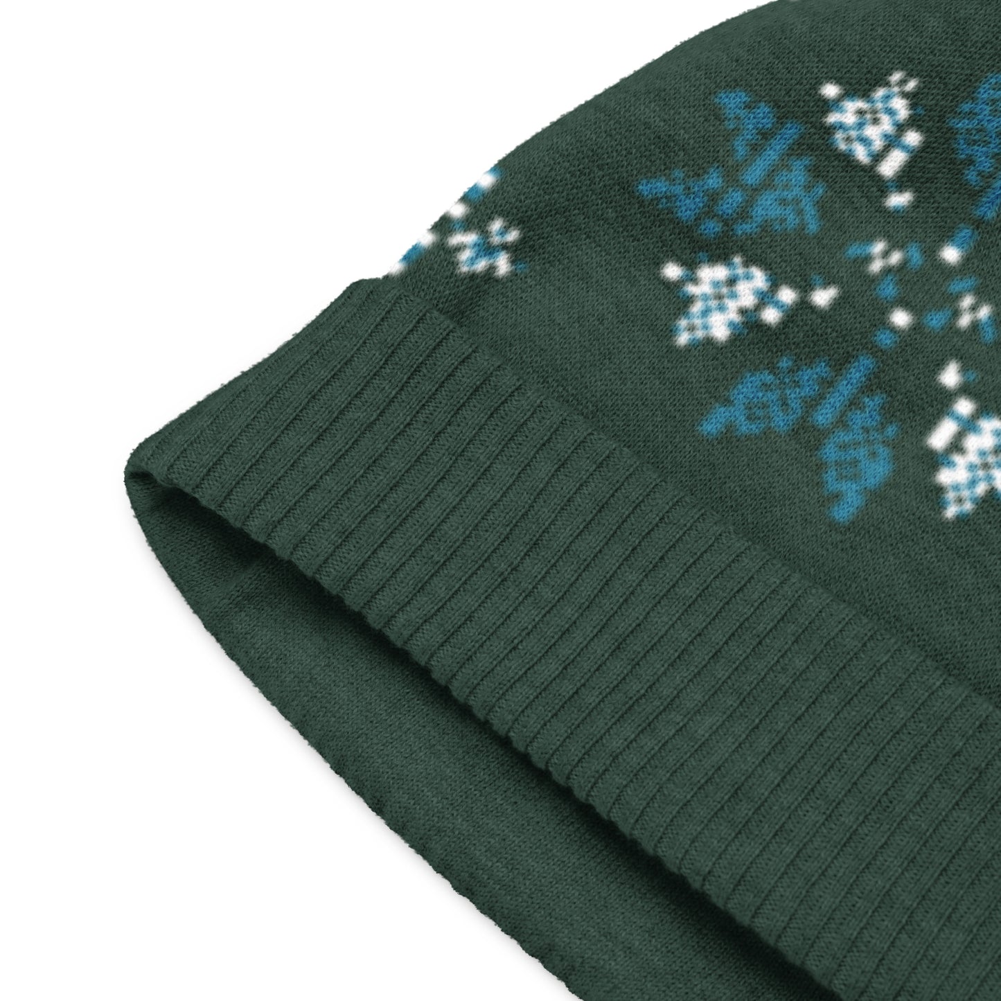 Close up of the dark green beanie showing ribbed trim and detailed winter pattern.