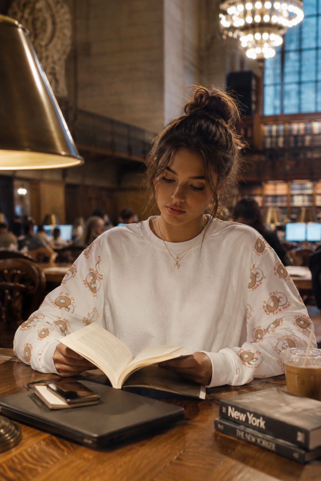 Gen Z woman reading inside New York Public Library wearing It Must Be The Water sweatshirt