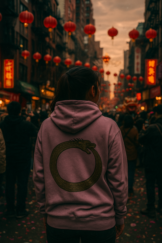 Person wearing a mauve hoodie with an Ouroboros design on the back while standing in a crowded street decorated with red lanterns.